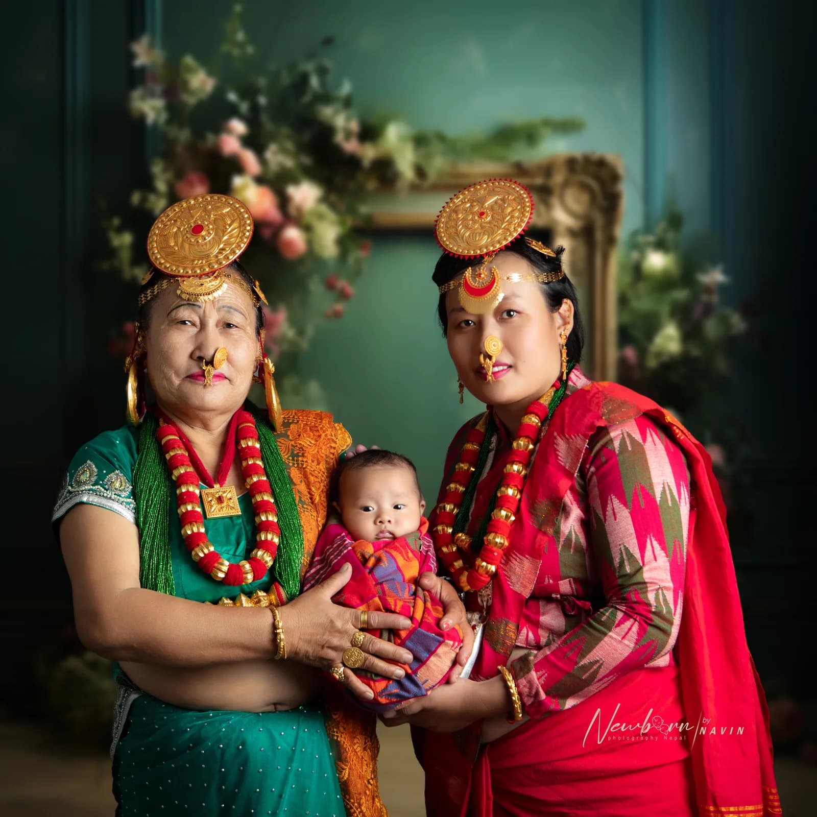 Three generations, grandmother, mother and newborn baby, dressed in traditional Nepali jewelry and clothing for a family portrait, with a floral backdrop.
